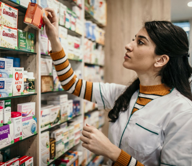 Female Pharmacist putting medicine on shelf