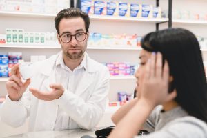 Pharmacist showing patient prescription, patient has panicked face