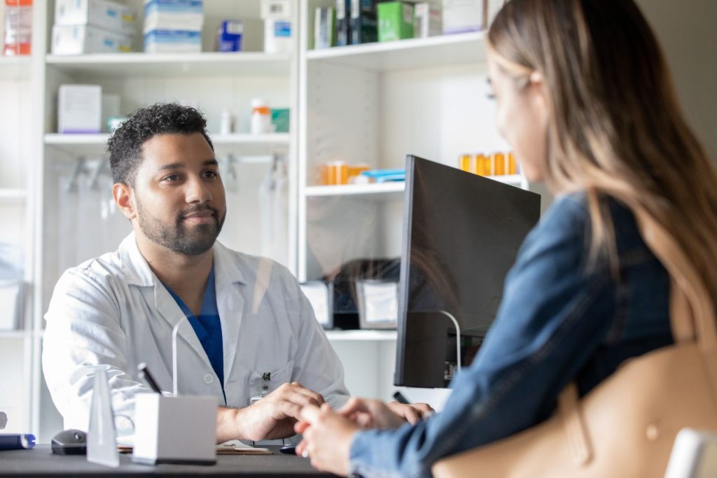Pharmacist on computer talking to patient